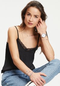 Zwarte camisole met kant, gecombineerd met zilveren sieraden en een horloge. Lichtblauwe denim jeans en witte sneakers maken de outfit compleet.