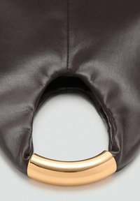 Sac à main en cuir marron avec une anse en métal doré courbé et une texture lisse. Le design comprend des bords arrondis et un trou pour la prise en main.