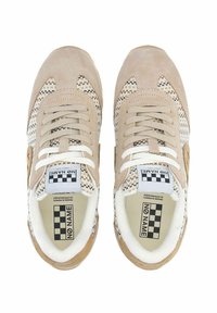 Sneaker beige con una parte superiore testurizzata, caratterizzata da motivi intrecciati, lacci bianchi e un logo sulla linguetta. Materiali in suede e tessuto utilizzati.
