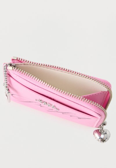 Ροζ πορτοφολάκι για κέρματα με φερμουάρ, ασημένιο φερμουάρ σε σχήμα καρδιάς και διακοσμητικά με κρυστάλλους στην μπροστινή τσέπη.