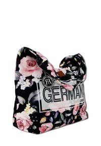 Zwarte bloemen tote bag met roze rozen en witte bloemen, voorzien van een 'GERMAN' label en een ronde merklabel. Zacht materiaal en casual ontwerp.