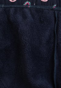 Marineblaue, plüschige Stoff mit weicher Textur; verfügt am oberen Rand über ein gemustertes elastisches Band mit bunten Details und einer glatten Oberfläche.