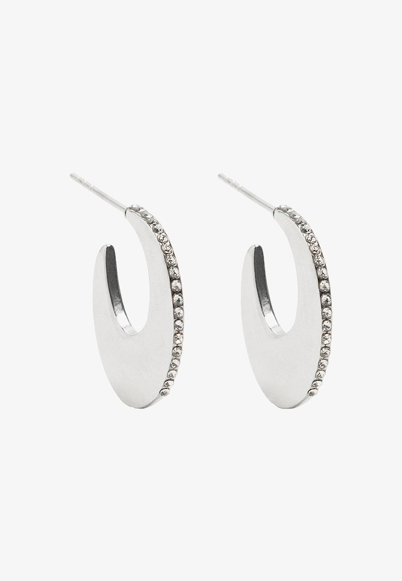 Srebrne kolczyki w kształcie obręczy o gładkim, zaokrąglonym wzorze, z rzędem małych przezroczystych cyrkoni wzdłuż jednej krawędzi.