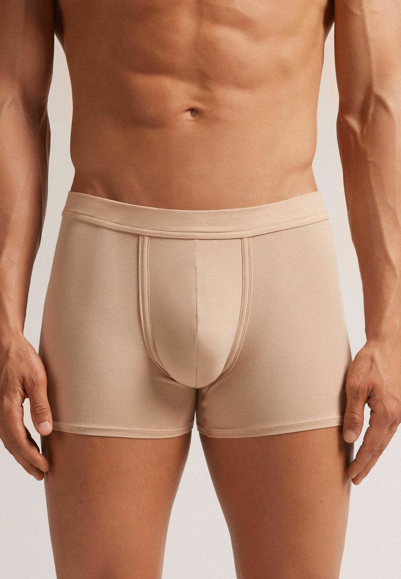 Beige boxer briefs with a smooth, stretchy fabric, featuring a contoured front pouch and a soft, elastic waistband. No visible patterns.
