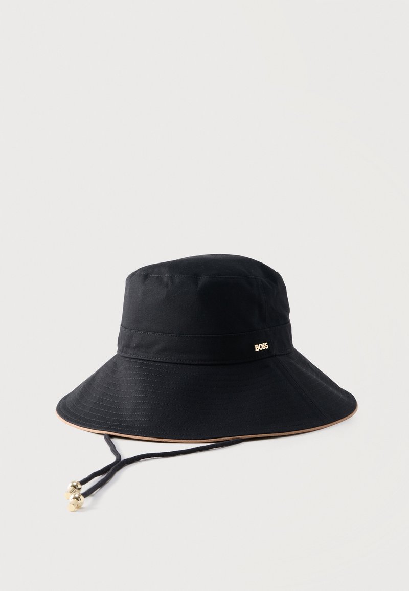 Chapeau bob noir à large bord avec sangle de menton réglable terminée par des perles dorées et un petit logo métallique "BOSS" sur la bande.