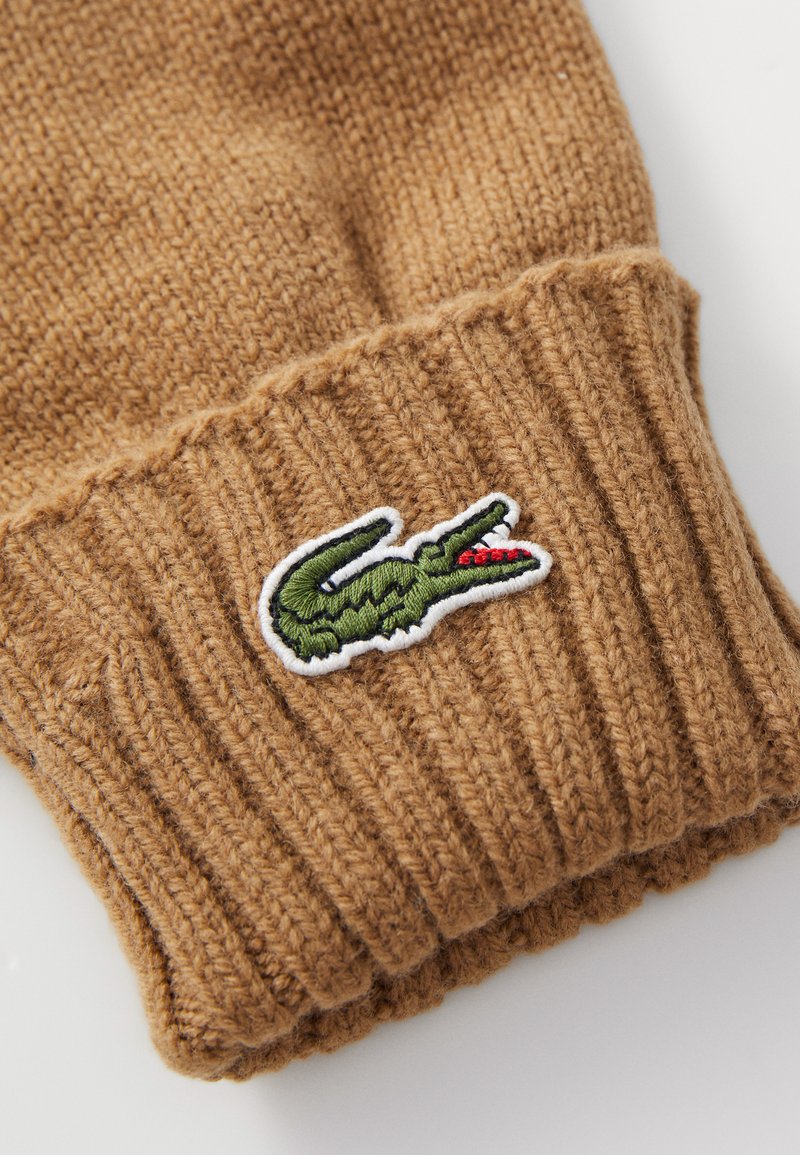 Brąkowa dziana rękawiczka z prążkowanym mankietem i zielonym haftowanym logo krokodyla z czerwonym akcentem z boku.