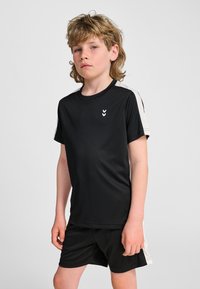 Czarna sportowa koszulka z krótkimi rękawami, zaokrąglonym dołem i białym logo w kształcie szewrona na piersi; zestawiona z czarnymi szortami z białymi akcentami po bokach.