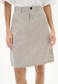 Jupe à rayures mi-longue en crème et noir, dotée d'une fermeture à boutons, de passants de ceinture et de poches latérales. Fabriquée en tissu texturé.