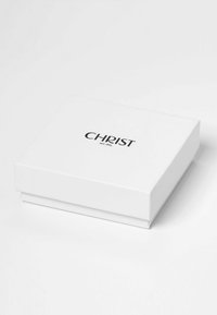 Weißer rechteckiger Karton mit schwarzem Text "CHRIST seit 1863", der zentriert auf dem Deckel platziert ist, auf einer weißen Oberfläche.