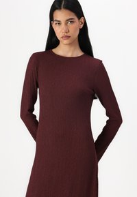 Bourgogne langermet kjole, ribbet tekstur, rund hals, slank passform, kne-length, minimale detaljer, egnet for ulike anledninger.