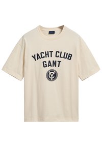 Camiseta de algodón beige con mangas cortas y cuello redondo, que presenta el texto en azul marino "YACHT CLUB GANT" y un diseño de logo circular.