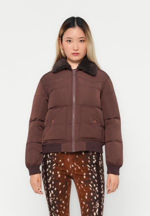 Puffer jacket in dark brown with a fur collar, featuring a front zipper, two pockets, and ribbed cuffs and hem. Paired with patterned pants.