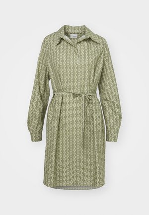 Πράσινο φόρεμα με μοτίβο, που διαθέτει κασκόλ στο λαιμό, μακριά μανίκια και ζώνη στη μέση. Διαθέτει επαναλαμβανόμενο γεωμετρικό σχέδιο σε μαλακό ύφασμα.