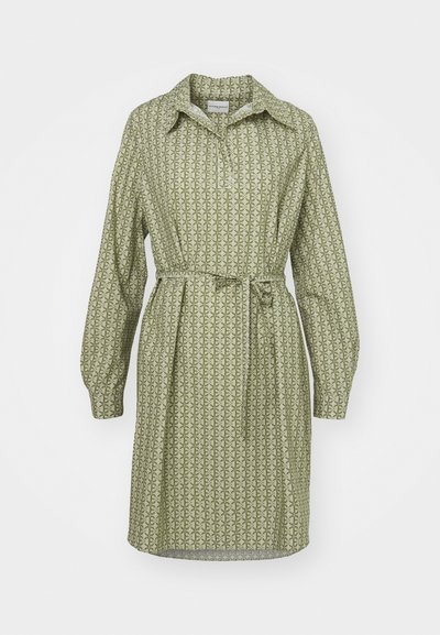 Πράσινο φόρεμα με μοτίβο, που διαθέτει κασκόλ στο λαιμό, μακριά μανίκια και ζώνη στη μέση. Διαθέτει επαναλαμβανόμενο γεωμετρικό σχέδιο σε μαλακό ύφασμα.
