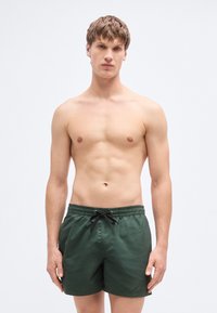 Πράσινα μαγιό σορτς με ελαστική μέση και κορδόνι, κατασκευασμένα από ελαφρύ ύφασμα, με λεία υφή και απλό σχέδιο.
