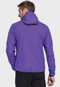 Lila leichte Jacke mit Kapuze, die eine glatte Textur und elastische Bündchen verfügt. Sichtbare Steppnähte setzen Akzente und die Passform ist lässig.