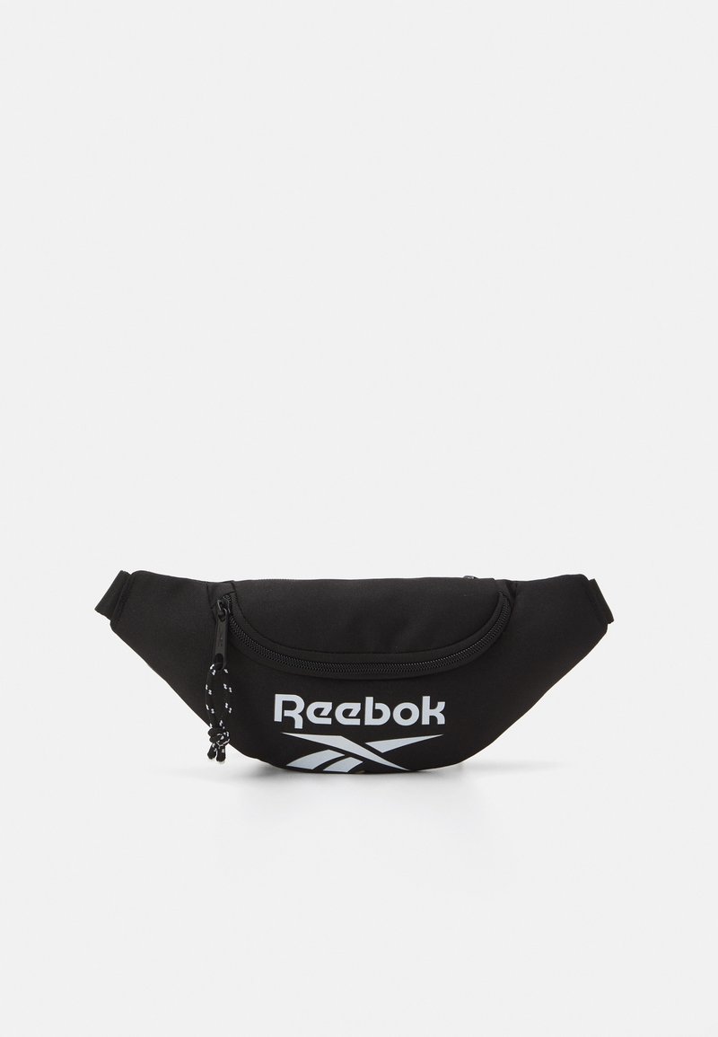 Čierna ľadvinka vyrobená z hladkej tkaniny, s kulatým tvarom, predným zipsom a výrazným bielym logom Reebok. Súčasťou je nastaviteľný popruh.