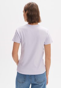 Lila T-shirt met korte mouwen en ronde hals, met een soepele textuur en een aansluitend ontwerp, gecombineerd met blauwe spijkerbroek.