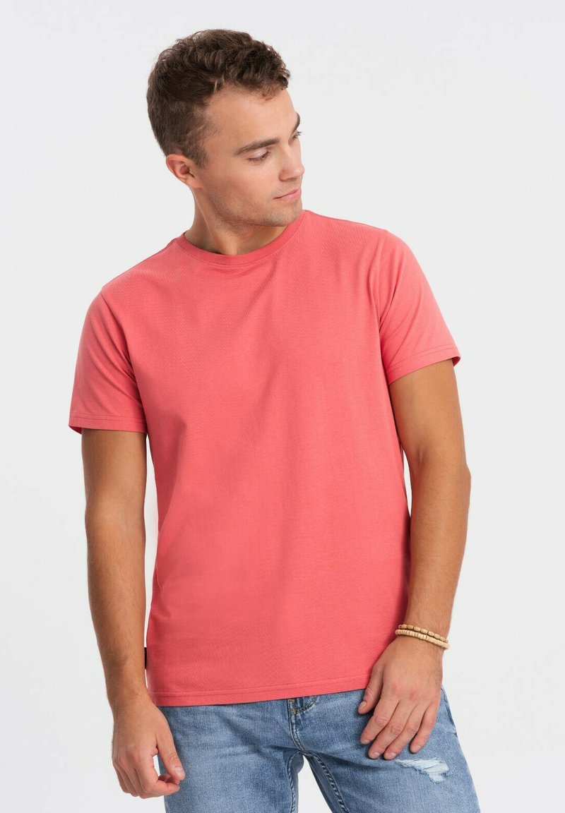 Koralfarvet t-shirt med korte ærmer lavet af bomuld, med en rund halsudskæring og en glat overflade, kombineret med lyseblå slidte jeans.