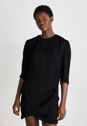 Musta lyhyt mekko, jossa on kolmen neljänneksen hihat, rento malli ja pehmeä tekstuuri. Ominaisuuksiin kuuluu pyöreä pääntie ja kevyet sivuhalkiot helmassa.