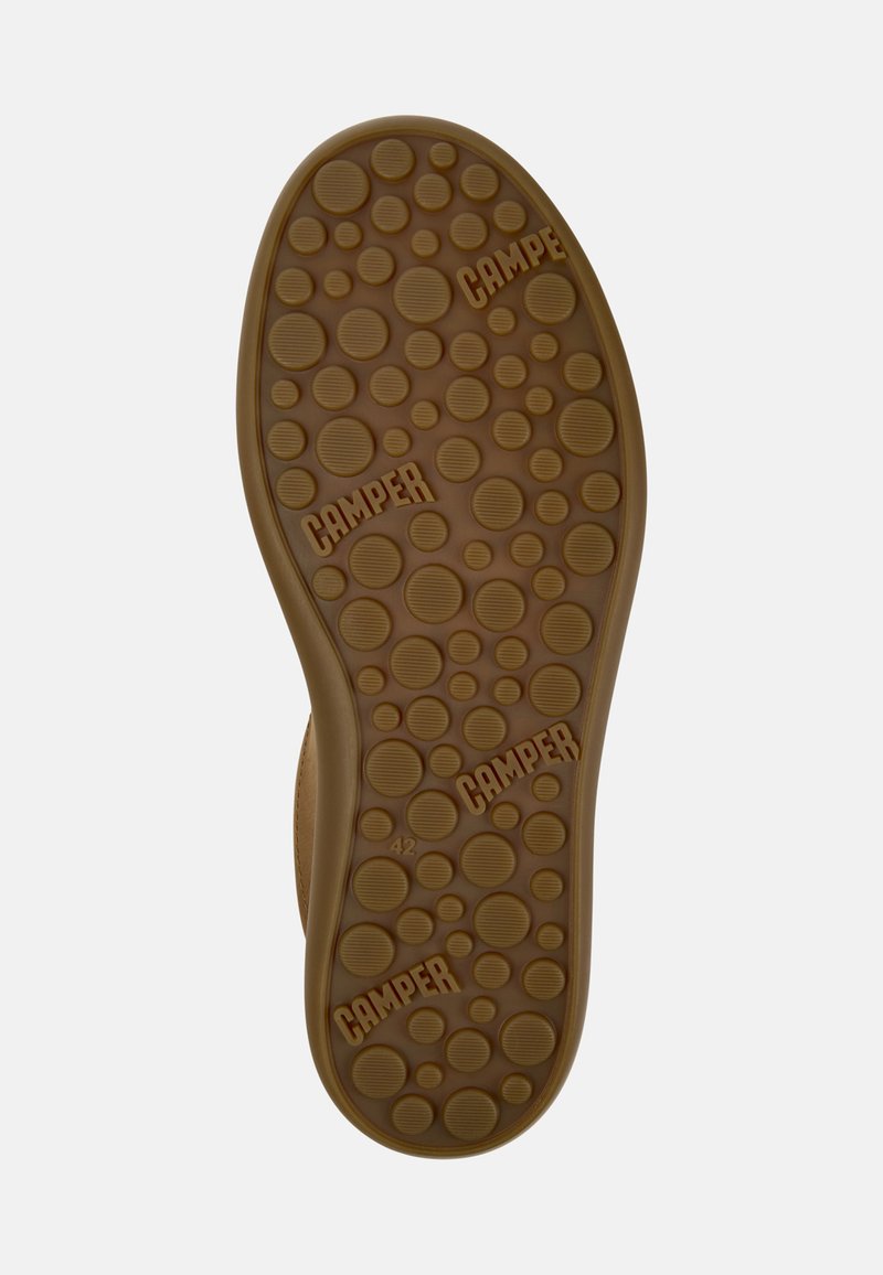 Brun gummisul med upphöjda cirkulära mönster och "CAMPER"-logotyp. Storlek 42 markerad på sidan, vilket ger ett texturerat grepp.