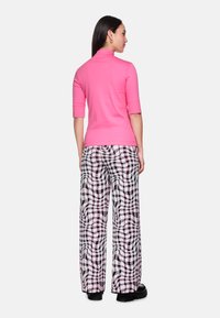 Fitted pink turtleneck top with short sleeves paired with wide-leg black and white checkered pants featuring a wavy pattern.