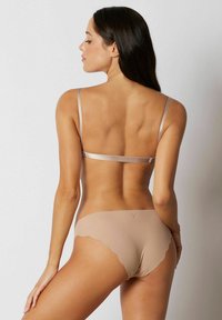 Naadloze huidkleurige lingerieset met een sculpted beha met dunne bandjes en een bijpassende scalloped hipster slip, gemaakt van zacht rekbaar materiaal.