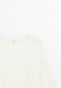 Lekki, luźno dziergany sweter w kolorze ecru. Ma okrągły dekolt i miękką teksturę. Metka głosi "Massimo Dutti Studio."