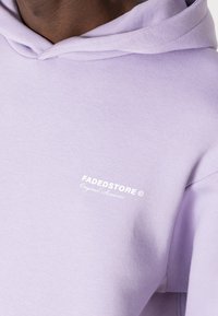 Felpa con cappuccio color lavanda, dotata di cordino, in morbido tessuto e con logo sul petto in testo bianco. Design semplice con una vestibilità comoda.