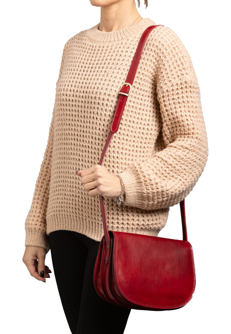 Borsa a tracolla rossa in pelle con una texture liscia, forma curva e tracolla regolabile. Presenta un design semplice e sobrio, privo di decorazioni.