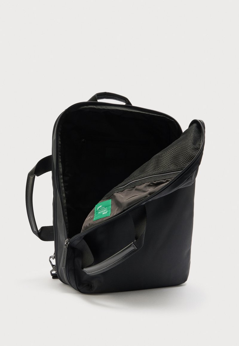 Zaino rettangolare nero con scomparto principale aperto che mostra una tasca interna con cerniera in rete e manici imbottiti su sfondo bianco.