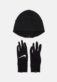 Cappello di lana nera a maglia con texture a coste, abbinato a guanti neri con il logo Swoosh bianco di Nike. Entrambi sono progettati per il freddo.