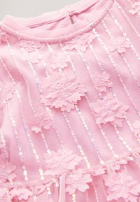 Roza tkanina z navpičnimi prosojnimi trakovi iz bleščic in plastnimi 3D cvetličnimi aplikacijami, všitimi na mehko okroglo izrez.