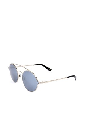 Lenti tonde con sfumatura blu, montatura sottile in metallo argento e terminali delle stanghette neri, inclinate verso destra su sfondo bianco.