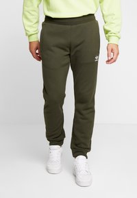 Mörkgröna sweatpants med smal passform, med sidfickor och en liten vit logotyp. Kombineras med vita sneakers. Slät tygkänsla.