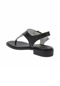 Sandale en cuir noir avec une semelle plate, design à sangle en T et boucle réglable à la cheville ; présente une texture lisse et un style minimaliste.