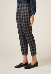 Niebiesko-szare spodnie w kratkę o dopasowanym fasonie, skróconej długo�ści oraz bocznych kieszeniach. Połączone z czarnymi, teksturowanymi mokasynami.