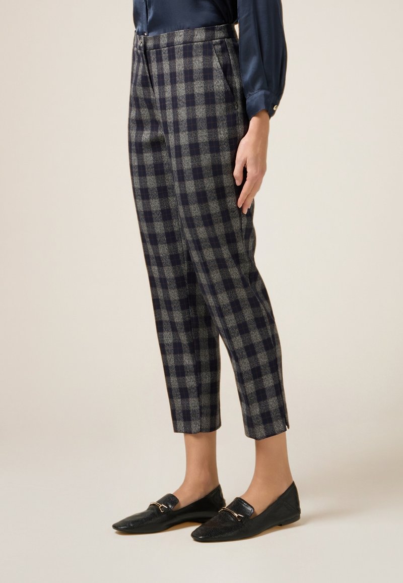 Niebiesko-szare spodnie w kratkę o dopasowanym fasonie, skróconej długości oraz bocznych kieszeniach. Połączone z czarnymi, teksturowanymi mokasynami.