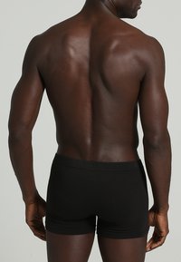 Svarta bomullshorts med tajt passform, med en mjuk elastisk midja och utan synliga mönster eller logotyper.