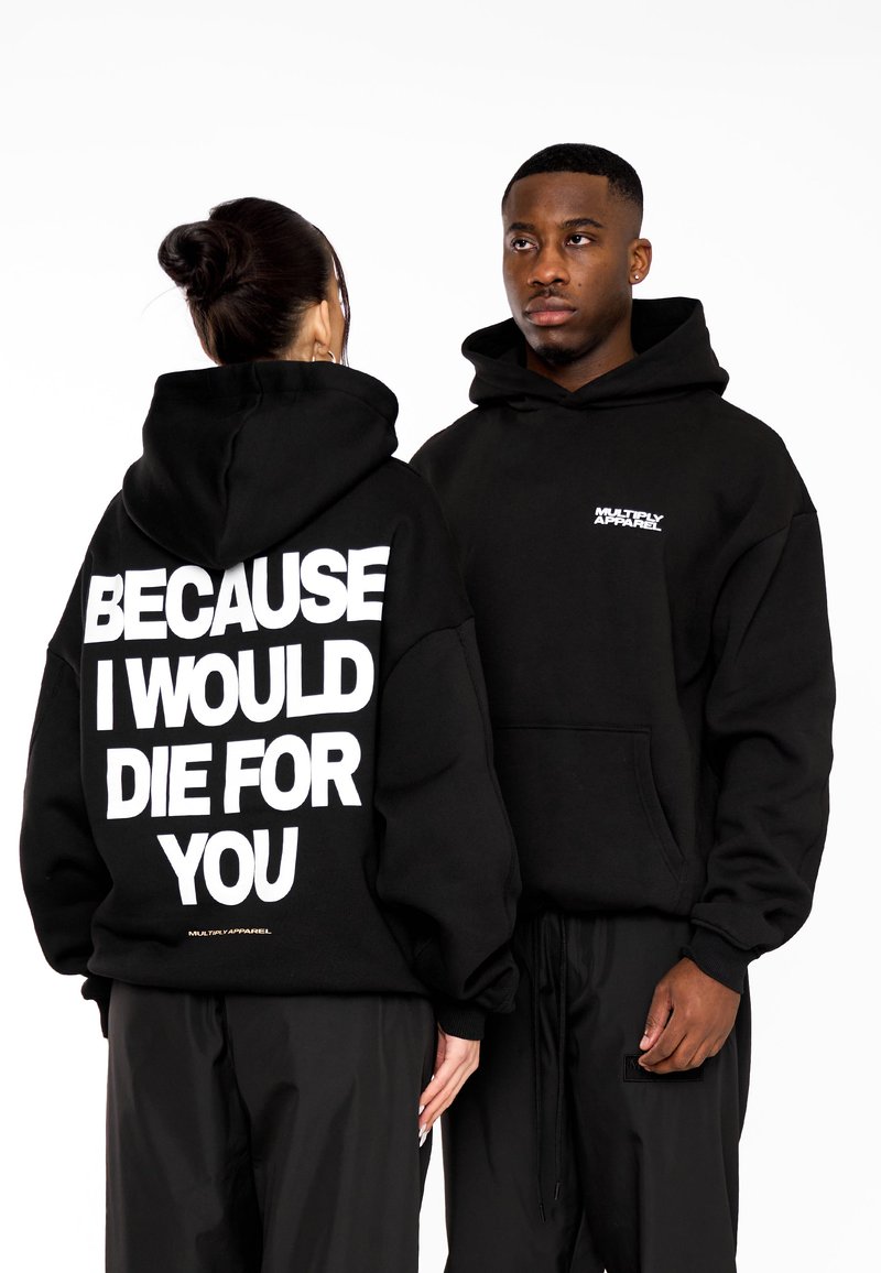 Sudaderas negras con corte oversize; el texto en blanco en la parte posterior dice "PORQUE MORIRÍA POR TI." Pequeño logo en el lado izquierdo del pecho. Textura de tejido suave.