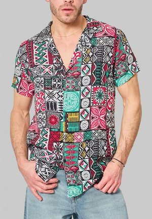 Chemise à manches courtes avec un design multi-patrons en rouge, vert, noir et blanc, avec une coupe décontractée et un col à revers.