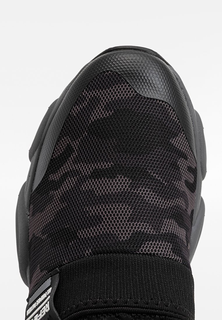 Baskets noires avec tige en mesh arborant un motif camouflage, des accents en caoutchouc texturé et un col élastique pour un ajustement snug.