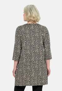Zwarte en beige tuniek met een geometrisch patroon, driekwartmouwen en een rechte snit, gemaakt van gestructureerde stof.
