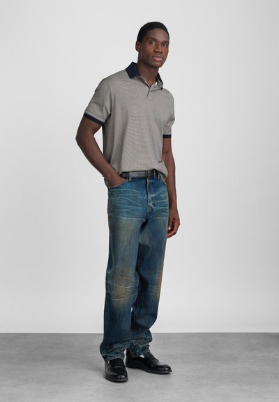 Polo skjorte med rutete mønster, marineblå krage, paret med blå denim bukser med slitte detaljer. Svarte sko fullfører antrekket.