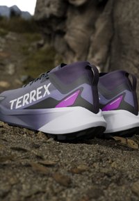 Scarpe da trail Terrex da uomo con una tomaia sintetica viola e grigia, una soletta bianca e un suola nera con grip testurizzato.