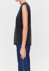 Zwarte mouwloze top met een ontspannen pasvorm, versierd met kleine, kleurrijke embellishments, gecombineerd met denim jeans. Glad materiaal en eenvoudig ontwerp.