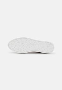 Semelle de chaussure en caoutchouc blanc avec une surface texturée et des motifs géométriques pour une meilleure adhérence. Marquée de la taille 37 près du talon.
