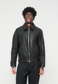 Black leather jacket with a zip front, point collar, and smooth texture, featuring a contrasting panel across the chest and long sleeves.