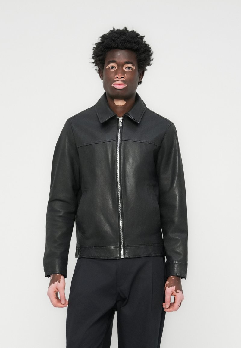 Black leather jacket with a zip front, point collar, and smooth texture, featuring a contrasting panel across the chest and long sleeves.