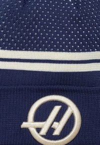 Granatowa dzianinowa czapka z teksturowanym wzorem, dwoma białymi paskami i haftowanym logo w jasnym odcieniu kremowym.